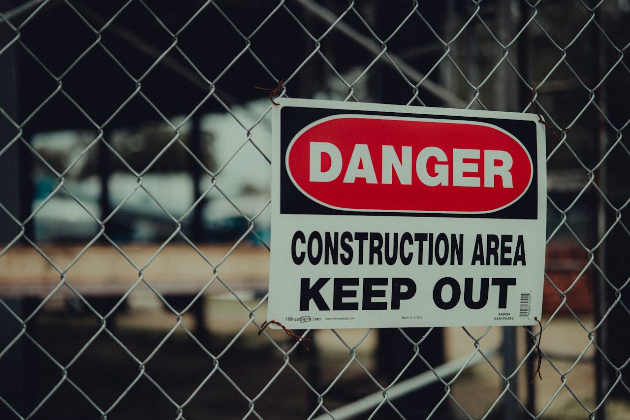 Danger construction area warning sign on a site fence